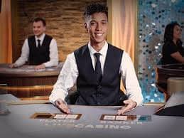 Layar permainan Infinite Blackjack dengan dealer dan meja pemain di studio live